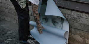 A tatooed arm gluing posters in Burnaby BC.